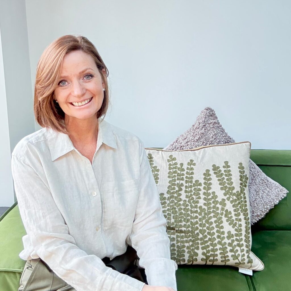 Debbie, founder of ClearSpace Home, sitting on a sofa and smiling